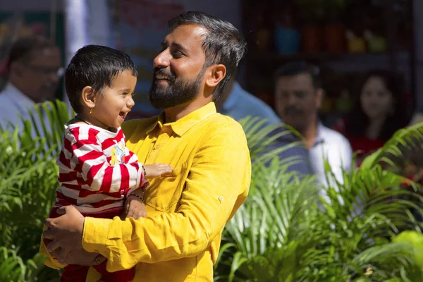 Young Indian man and son smiling, Empress garden, Pune