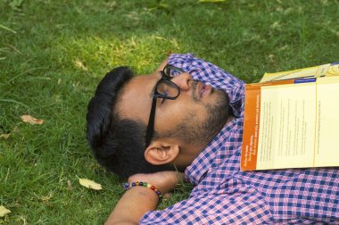 Çim üzerinde yalan ve okuduktan sonra dinlenme genç adam