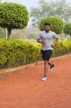 Genç adam bir koşu parkuru üzerinde çalışan 