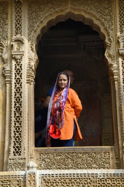 Jaisalmer, Rajasthan, Hindistan, Kasım 2018, Kothari 'den Patwon ki Haveli' nin ağır oyulmuş penceresinin içindeki turist