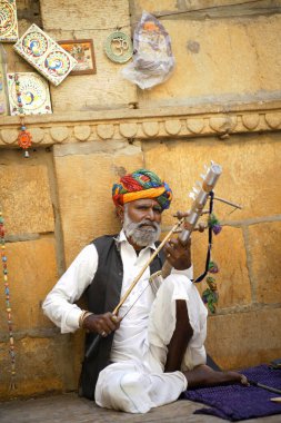 Jaisalmer, Rajasthan, Hindistan, Kasım 2018, geleneksel müzik aleti çalan geleneksel kostümlü yerel sanatçı