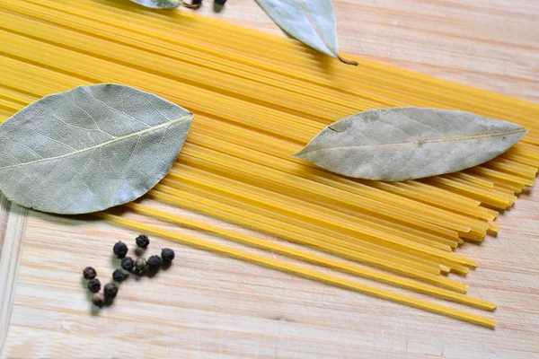 Raw spaghetti and laurel leaves on a wooden background