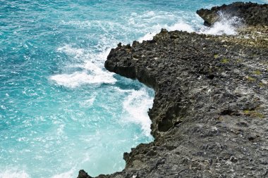 Bir okyanus Sahili, sıçrama, mavi su dalgaları üzerinde kayalık uçurum