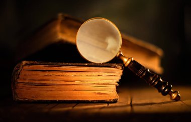 ahşap masa üzerinde antik büyüteç ile eski kitaplar