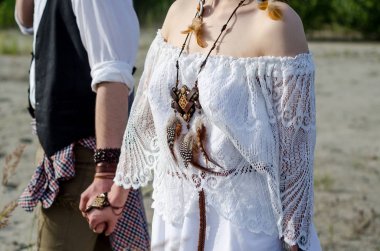 Boho düğün birkaç yakın çekim. Beyaz etnik elbiseli adamla elele şık hippi kadını. Tılsım dreamcatcher eşarplı boynunda giyiyor