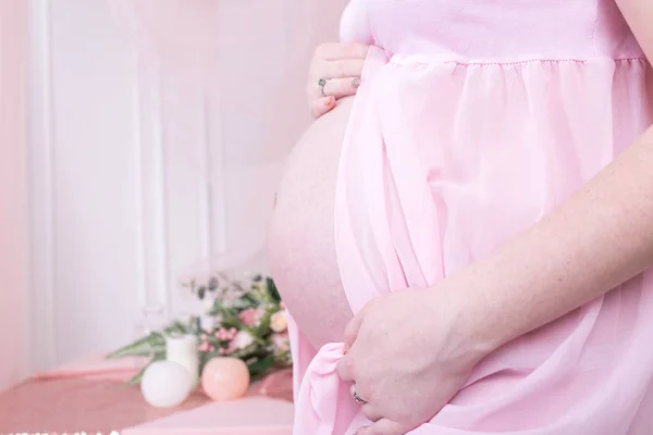 임신한 여자는 그녀의 만지기의 닫습니다 배경에서 분홍색 드레스에 — 스톡 사진