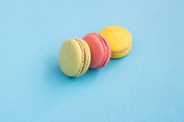 Pembe, sarı ve yeşil macaroons mavi zemin üzerine. Parlak ve renkli kavramı. Copyplace, metin için yer. 
