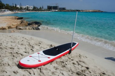 Paddle kurulu deniz arka plan ile ayağa, kumdan tahtada sup 