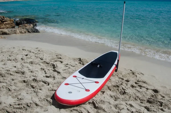 Paddle kurulu deniz arka plan ile ayağa, kumdan tahtada sup 