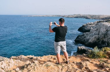 Adam Gezgin alarak fotoğraf ile cep telefonu ayakta deniz kenarında. H