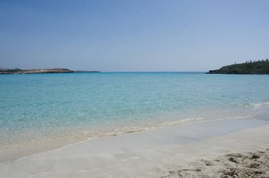 Akdeniz kumsalda. Hafif mavi su ve beyaz kum. Par