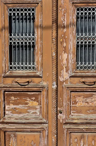 Une partie de la vieille porte décolorée marron avec de la peinture fissurée avec treillis gagner — Photo