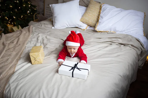 Bébé garçon avec cadeau de Noël sur le lit à la maison — Photo