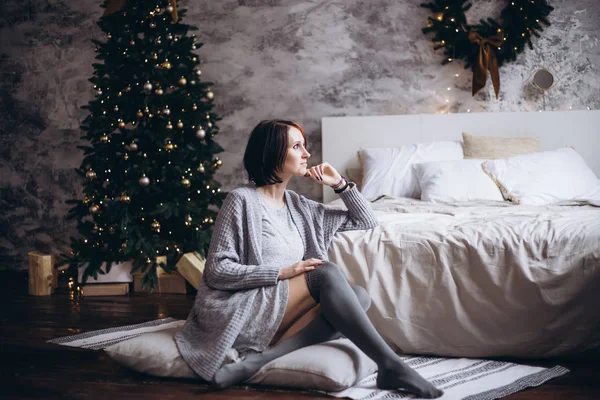 Ung vacker kvinna i varma mysiga kläder hemma nära julgranen — Stockfoto