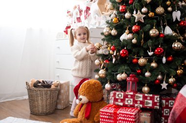 Küçük kız evde Noel ağacı süslüyor.