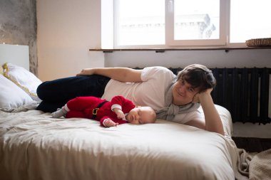 Baba ve bebek evdeki yatakta yatıyorlar.