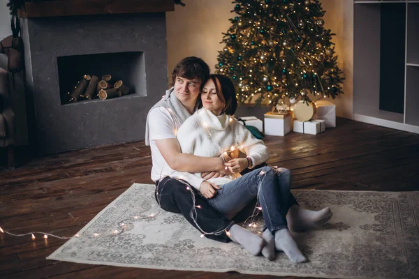 Pareja enamorada sentada junto a un árbol de Navidad en casa — Foto de Stock