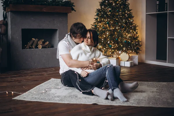 Feliz casal apaixonado sentado ao lado de uma árvore de Natal em casa — Fotografia de Stock