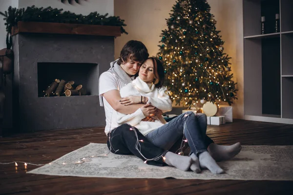 Pareja celebrando Navidad y días festivos felizmente cerca de árbol de Navidad bellamente decorado, concepto de Navidad — Foto de Stock