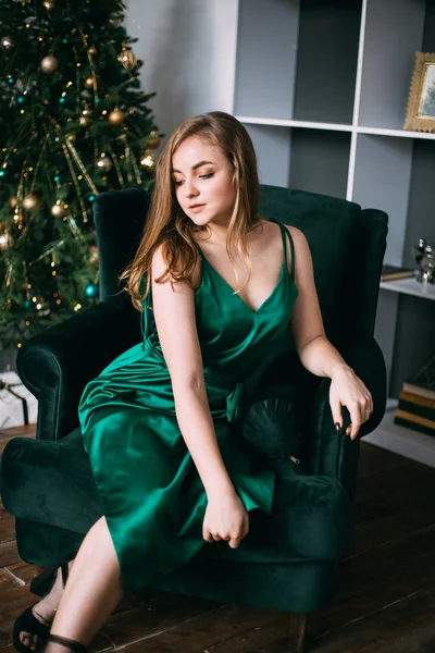 Joven mujer guapa en vestidos verdes por la noche cerca del árbol de Navidad decorado. — Foto de Stock