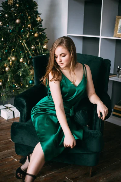 Mujer vestida de verde sentada en sillón cerca del árbol de las christmas, año nuevo. — Foto de Stock