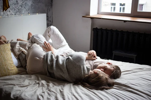 Glückliches junges Paar bleibt zu Hause am Fenster im Bett — Stockfoto