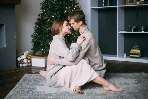 Νεαρός άνδρας και γυναίκα αγκαλιασμένοι πάνω από το χριστουγεννιάτικο δέντρο — Φωτογραφία Αρχείου