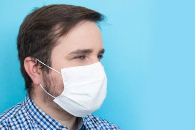 Maskeli adam mikropları, zehirli dumanları ve toz bulutlarını önlemek için mavi arka planda, kopyalanmış mekanda, kopyalanmış mekanda metinler için izole edilmiş. Bakteriyel enfeksiyonun önlenmesi Coronavirüs