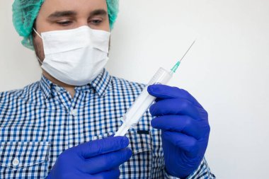 Biyolojik tehlike. Koronavirüs salgını. Koruyucu giysili ve maskeli bir adam şırınga ve aşı taşıyor. Grip aşısı, koronavirüs, ebola.,