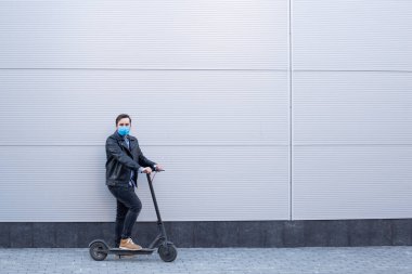 Elektrikli scooter 'da Coronavirus' a karşı koruyucu maskeli bir adam. Hastalıktan korunma. Sağlık güvenliği kavramı COVID-19.