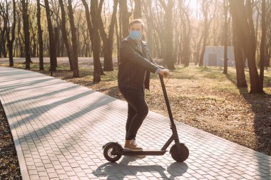 Elektrikli scooter kullanan koruyucu maske takan bir adam, sağlık hizmeti kavramı. Coronavirüs karantinası.