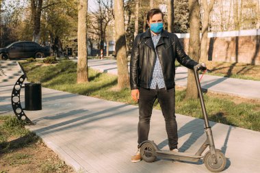 İş adamı koruyucu maske takıyor elektrikli scooter kullanıyor, sağlık hizmeti kavramı. Coronavirüs karantinası.