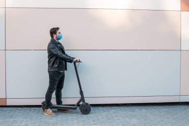 İş adamı koruyucu maske takıyor elektrikli scooter kullanıyor, genç adam tıbbi maske takıyor. Coronavirus konsepti. solunum koruması