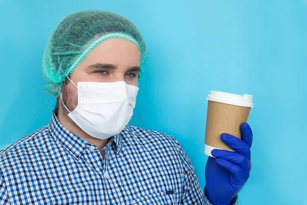 Exhausted doctor with coffee cup wearing coronavirus protective mask uniform. Coronavirus Covid-19 outbreak. Mental state of medical professional. Overworked health workers