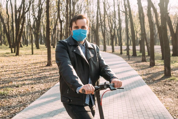 Man in protective face mask using electric scooter. Coronavirus, illness, infection, quarantine, medical mask