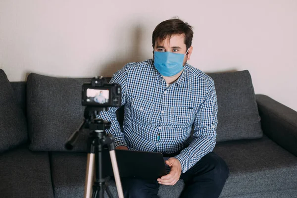 Man recording video blog tells how to protect yourself from 2019-nCov. Blogger talks mers-cov how to use of alcohol wipes, thermometer. Influencer man blogger in medical mask talks about coronavirus.