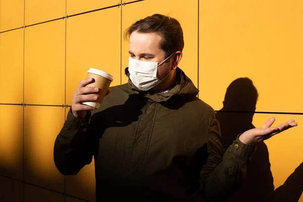 Man in mask with cup of coffee, coronavirus, illness, infection, quarantine, medical mask