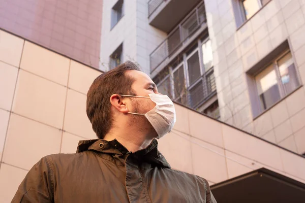 Man in medical mask on the street near buildings. Coronavirus man mask