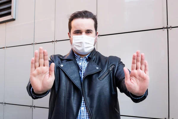 man showing with his hands gesture stop. man wears protective mask against infectious diseases and flu. health care concept. coronavirus quarantine.