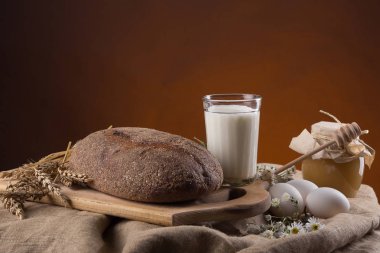 Ekmek bir ahşap tepsi, bal, süt ve yumurta ile cam bir kavanoz içinde
