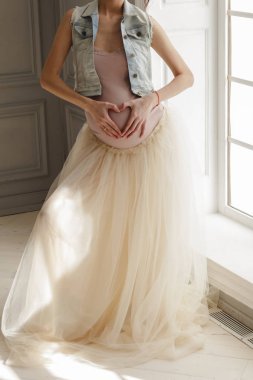 Birlikte bir aşk kalp şekli oluşturan ellerini tutan çekici bir hamile kadın portresi