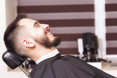 Genç bir adam bir kuaför bir sandalyede oturuyor Dükkanı ayısını traş