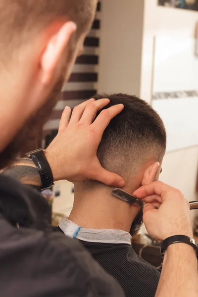 Shaving process at barbershop. Young bearded man getting haircut — Stock Photo, Image