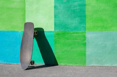 bir kaykay uzun tahta yaz aylarında parkta parlak yeşil bir duvarın yakınında duruyor. Arka plan. hiçbir kişi