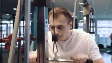 Genç adam spor salonunda antrenman yapıyor.