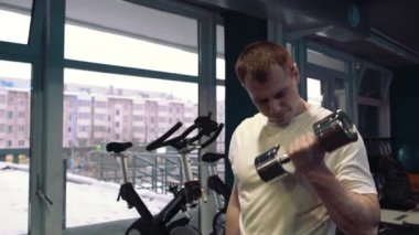 Genç bir adam, pazı dumbbells ile yapıyor. Güç ve motivasyon