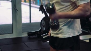 Genç bir adam, pazı dumbbells ile yapıyor. Güç ve motivasyon