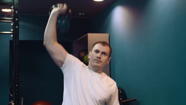 Fitness man gör en styrketräning genom att lyfta tung kettlebell. Yong idrottsman gör kettlebell gungor. Bodybuilder lyft kettlebell — Stockvideo