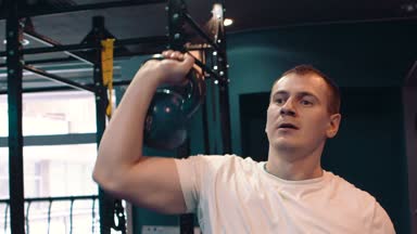 Fitness adam ağır kettlebell kaldırarak bir ağırlık çalışması yapıyor. Yong atlet kettlebell yapıyor salıncaklar. Vücut geliştirmeci kaldırma kettlebell