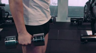 Genç bir adam, pazı dumbbells ile yapıyor. Güç ve motivasyon